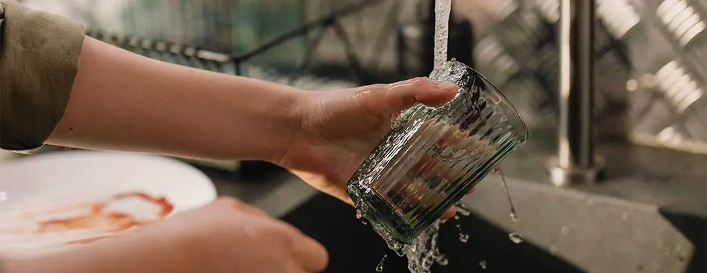Person washing a drinking glass