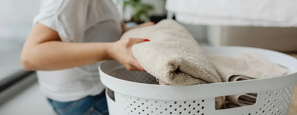 Placing folded towels in a laundry basket