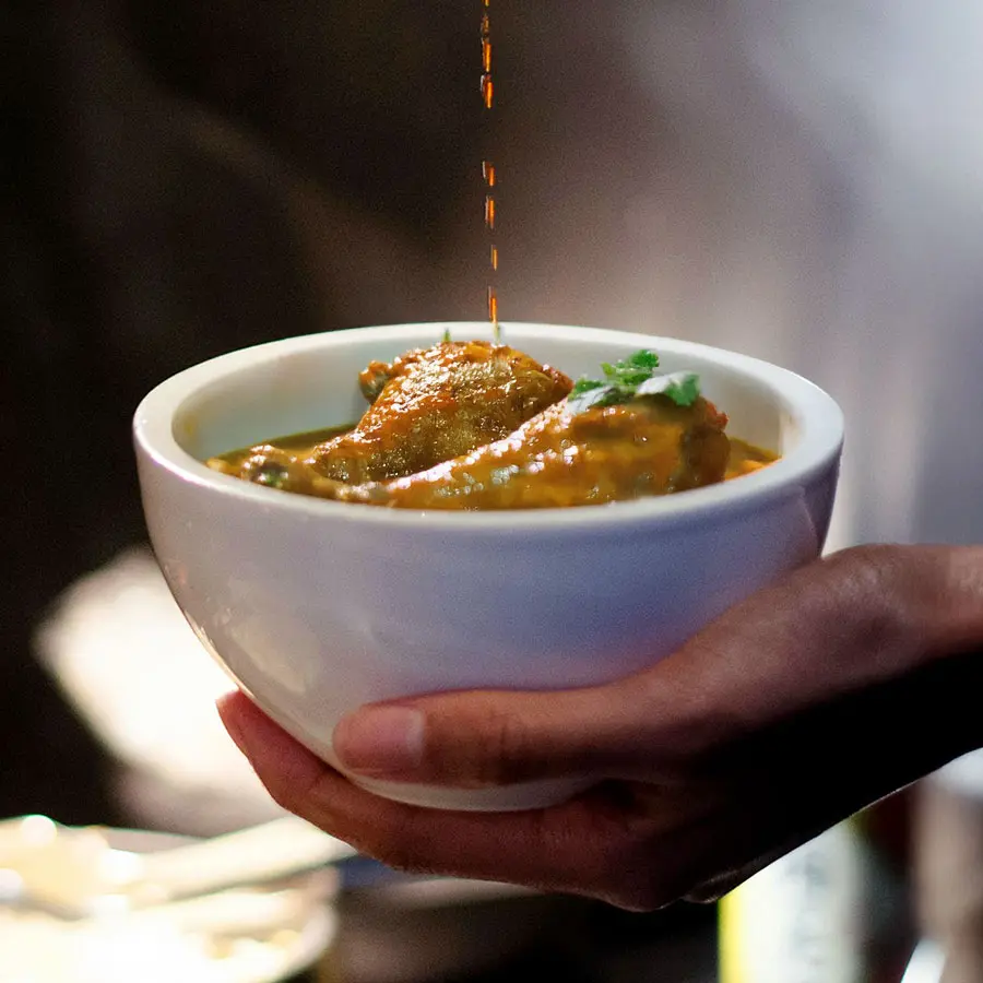 Gravy pouring into a bowl of Asian chicken curry