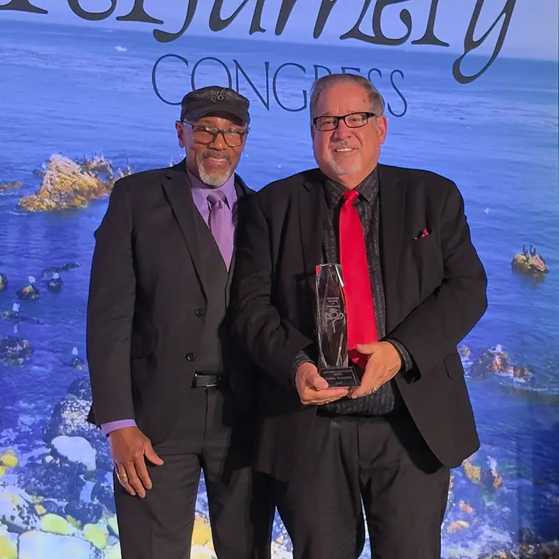 Roger Howell, President of the American Society of Perfumers together with John Gamba, Senior Perfumer, holding the award