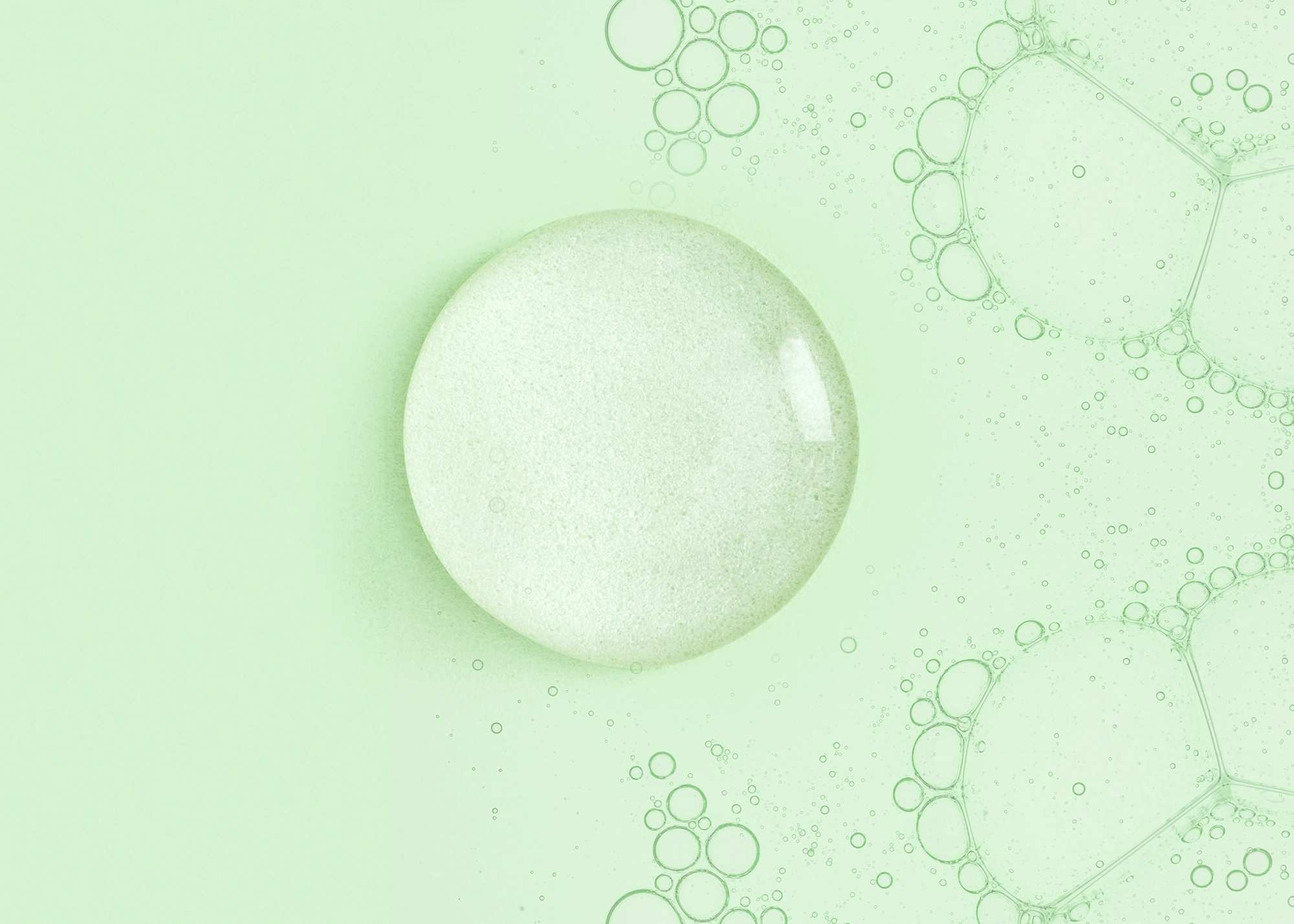 A pale green macro image of a large translucent bubble among clusters of smaller bubbles, evoking a fresh, calm, soap-like atmosphere.