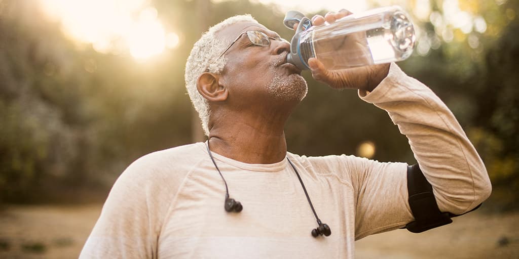 Elderly jogging man drinking from water bottle