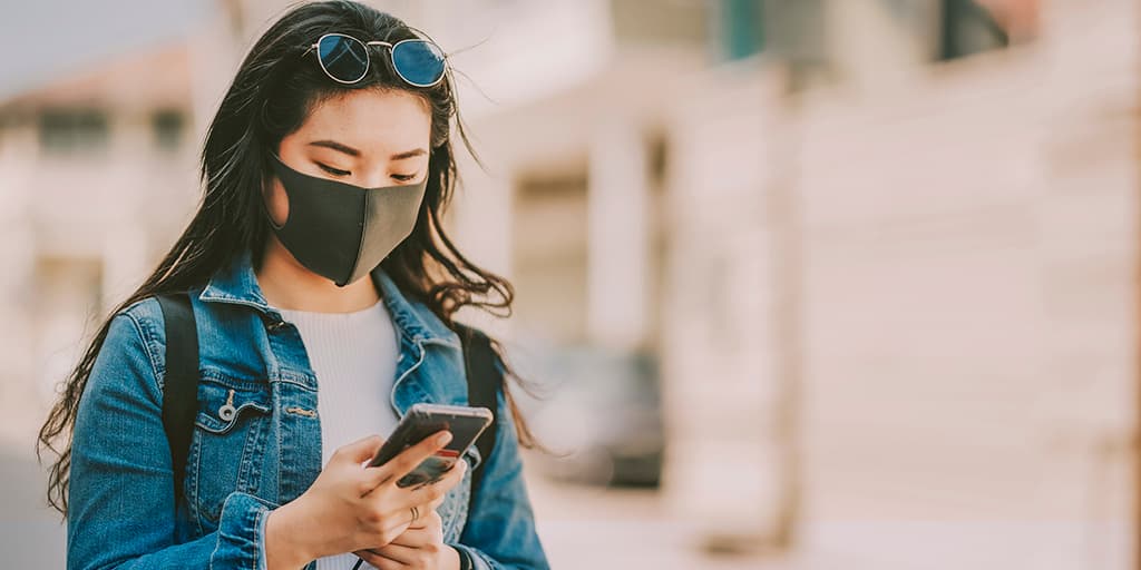 Young woman with facemask using mobile phone