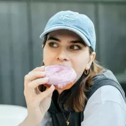 Young woman eating a coated dougnut with sprinkles