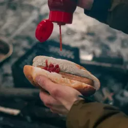 Adding ketchup to a hot dog