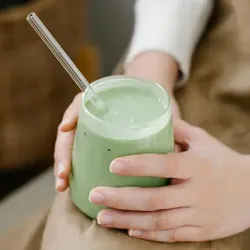 A person holding a green smoothie
