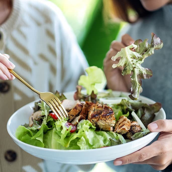 Two woman eating salad