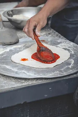 Adding sauce on top of a pizza