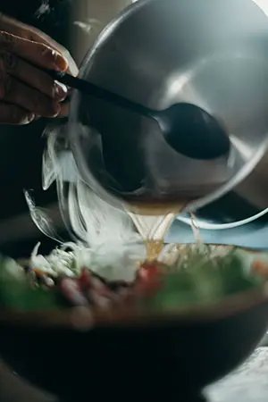 Pouring hot sauce in bowl with food