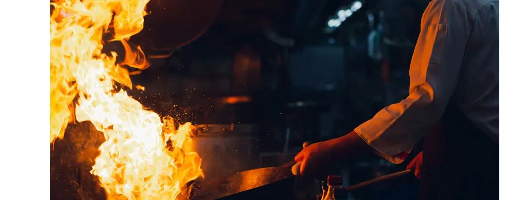 Chef tossing wok over high flame