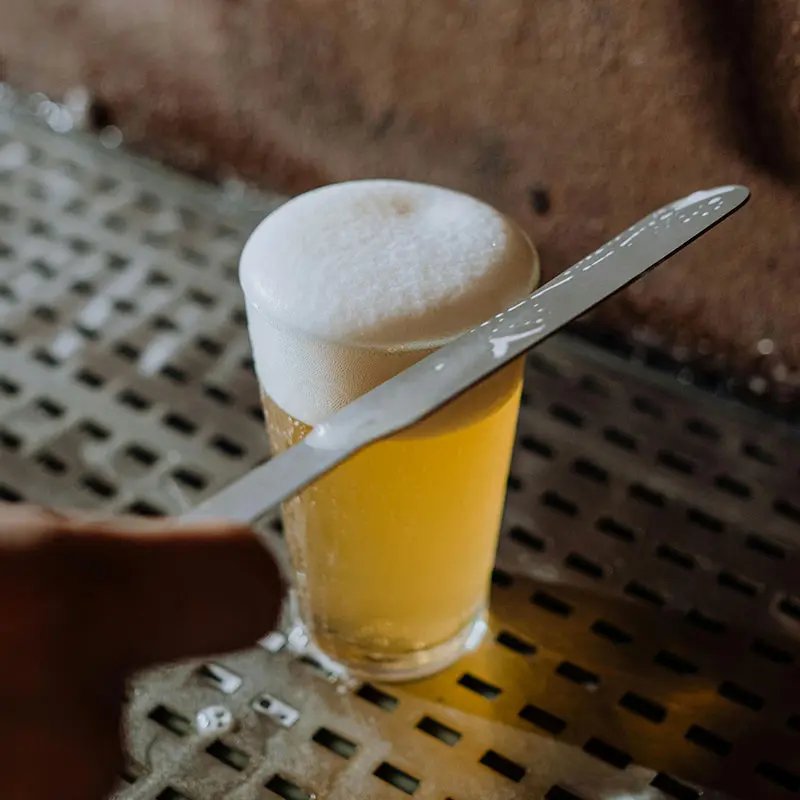 A knife over a glass of beer removing excess foam