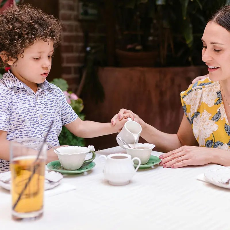 A person and child sitting at a table drinking tea