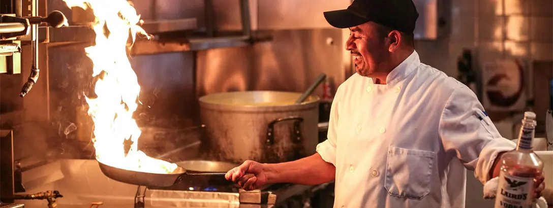 A chef in a black hat cooking in a kitchen