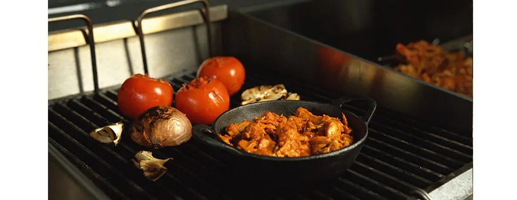 Tomates, onions, garlic and a plate with grilled meat on a barbecue
