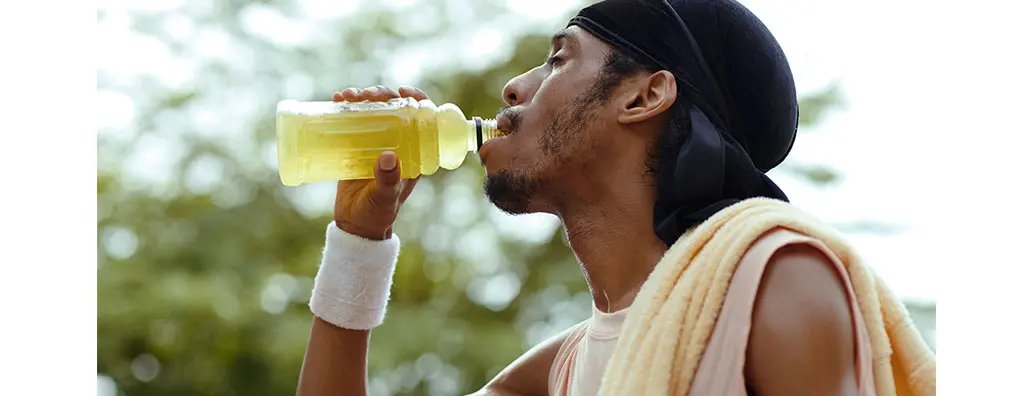 Young guy drinking a sports drink outdoors after working out