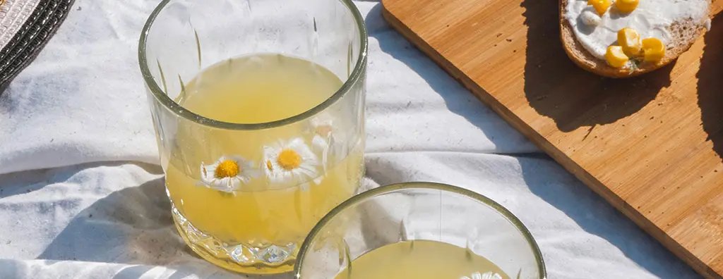 Two glasses with ice tea with floating flowers in it