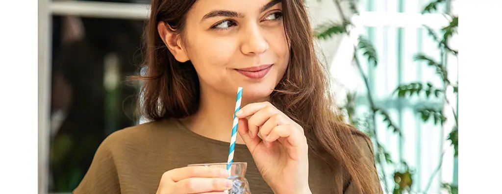 Young woman holding a beverage with a straw