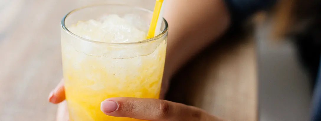 Someone holding a carbonated soft drink with ice and yellow and white straws
