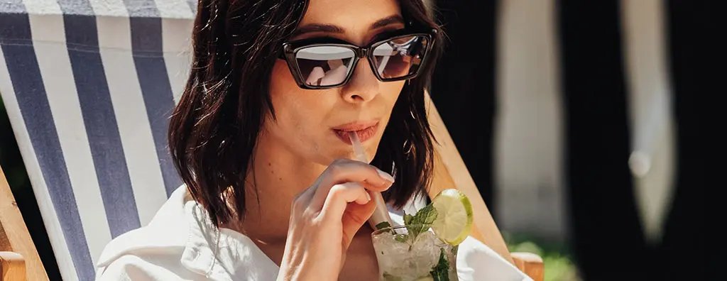 Woman in a beach chair drinking a beverage using a straw