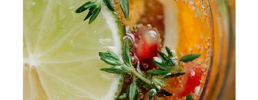 View from above on a beverage decorated with a lime slice, berries and herbs