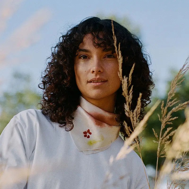 Woman with dark curly hair in the middle of a pampa field