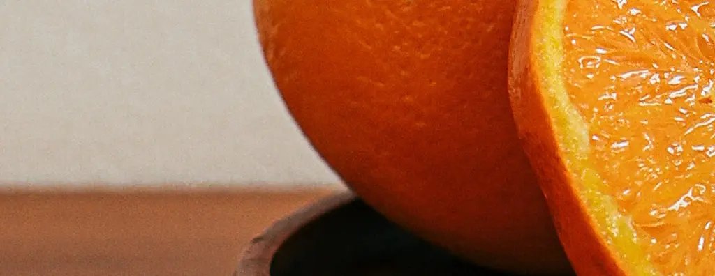 A cut orange and orange juice on a wooden serving tray on a wooden table