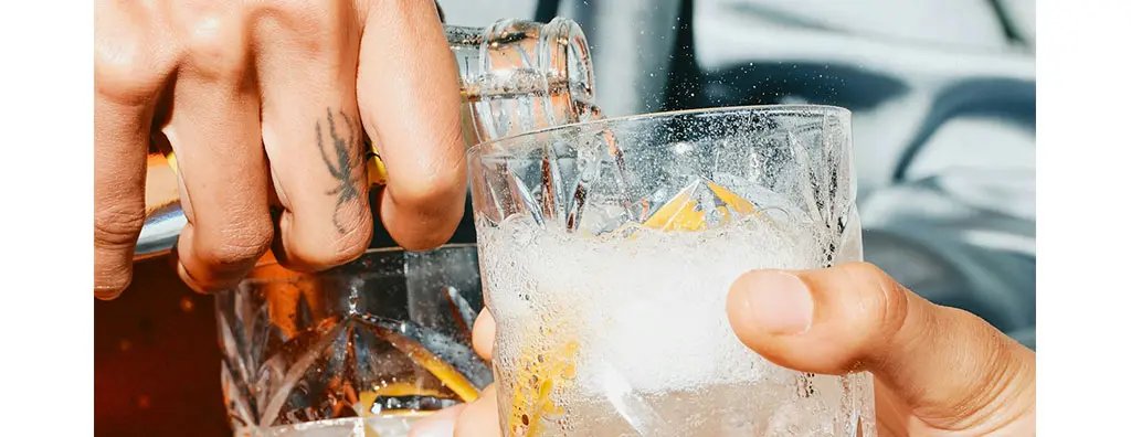 Pouring drinks in a glass with ice and lemon