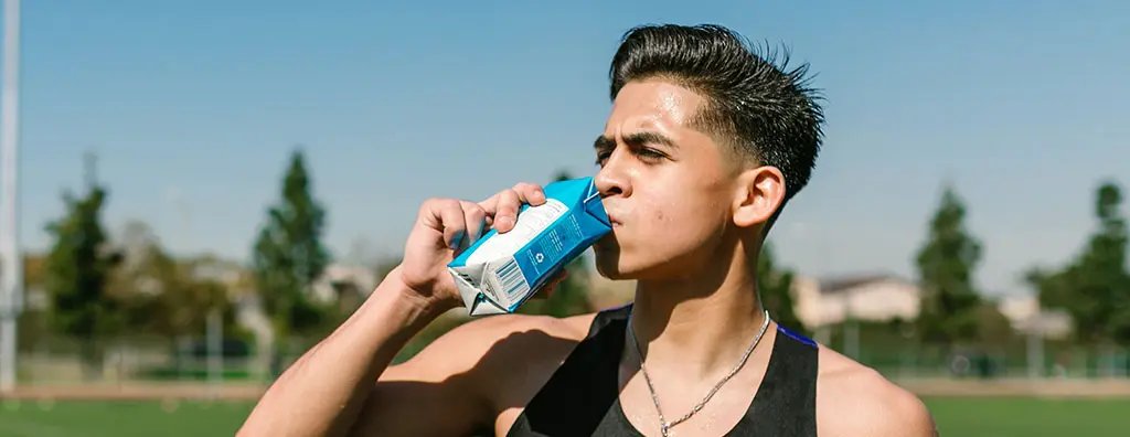 Close up of a man drinking a beverage from a beverage carton