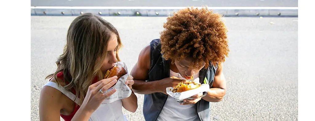 Two young people enjoying a hamburger with ketchup