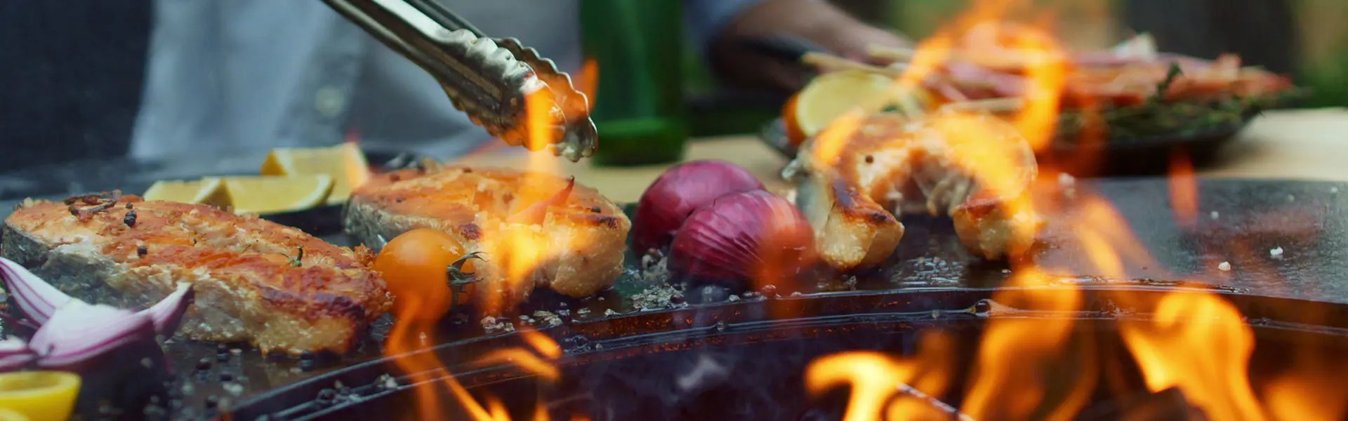 A close up of a barbeque with meat and vegetables