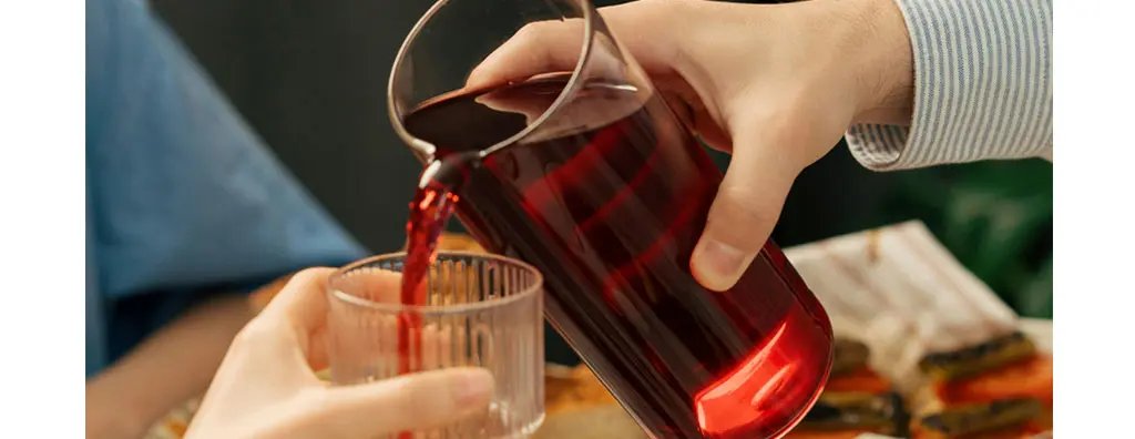 Close up of pouring a red beverage into a glass
