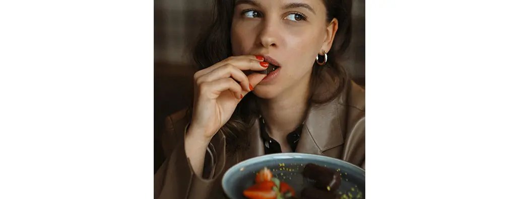 A woman enjoying a piece of chocolate