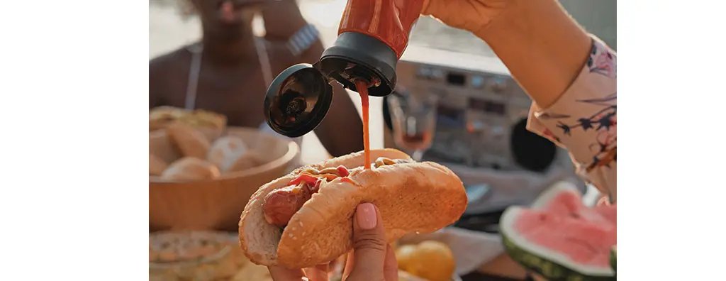 Adding tomato sauce on a hot dog
