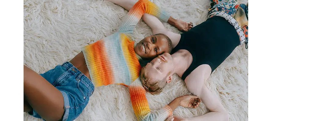 A young woman and man laying on a carpet