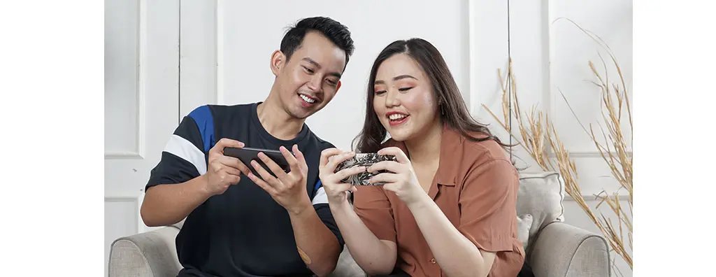 Two young people playing games on their mobile phones