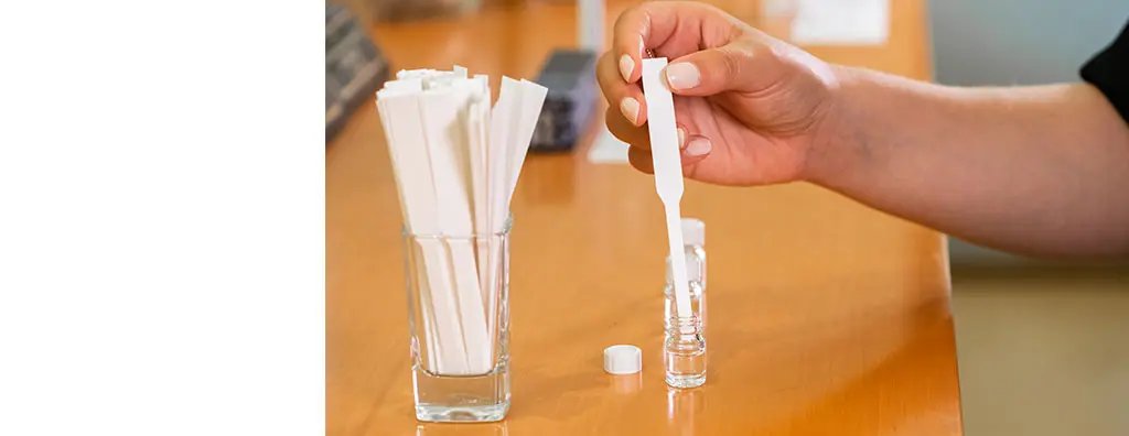 Glass with smelling strips and one smelling strip in a small glass bottle with oil