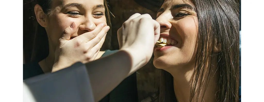 Young women playfully eating crisps
