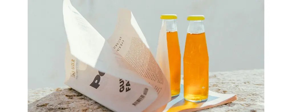Two bottles with an orange beverage on a magazine