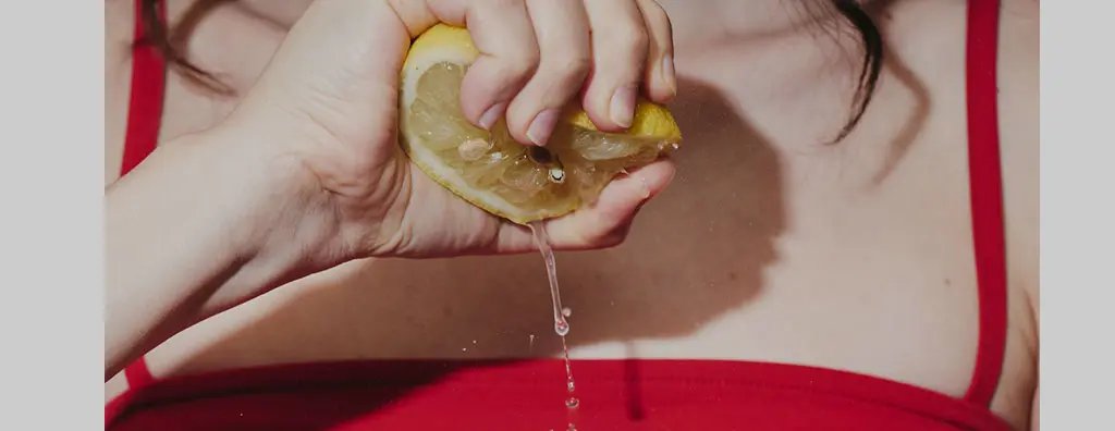 Squeezing half a lemon into a glass