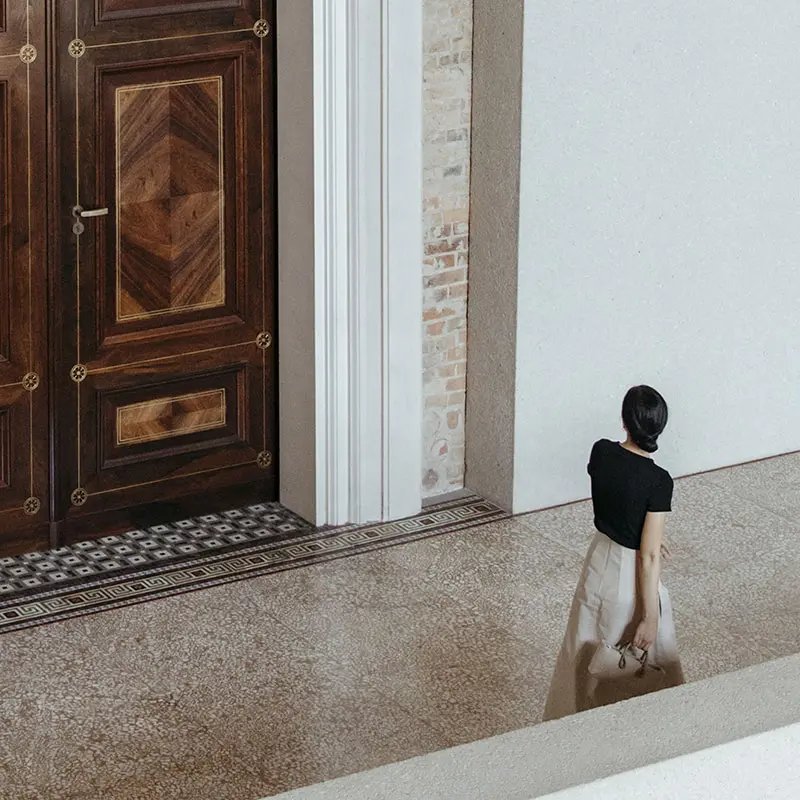 Large wooden door while a woman is passing through the hallway