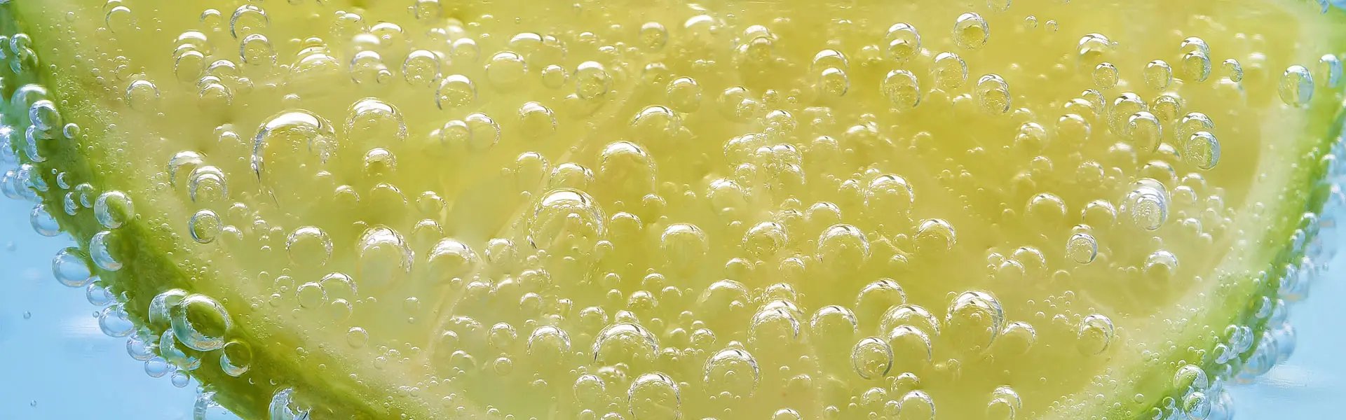 A close up of a slice of lime in a carbonated beverage