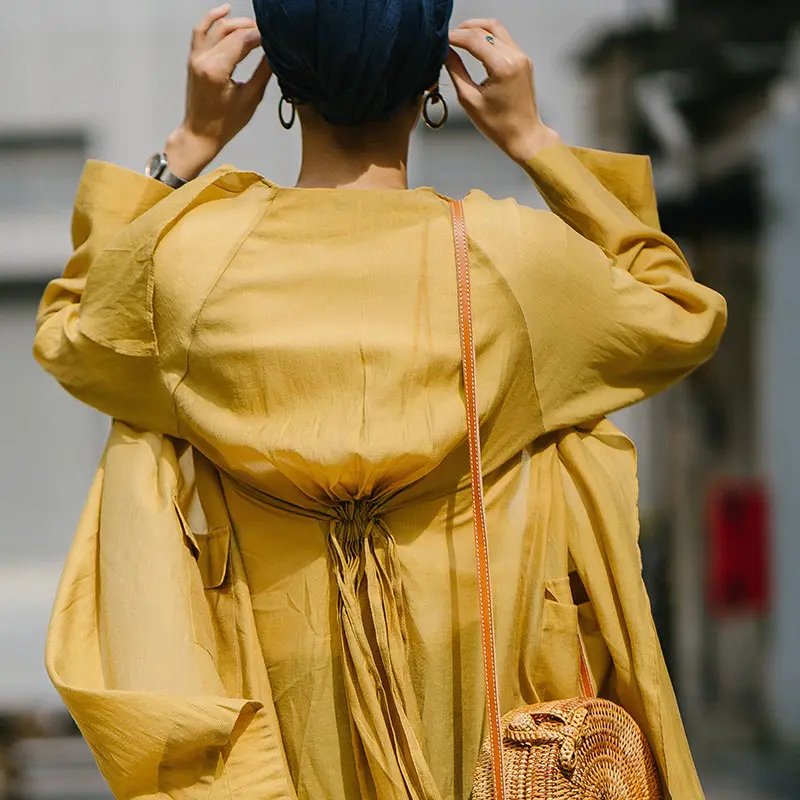 Woman backside, wearing a ambery trench coat