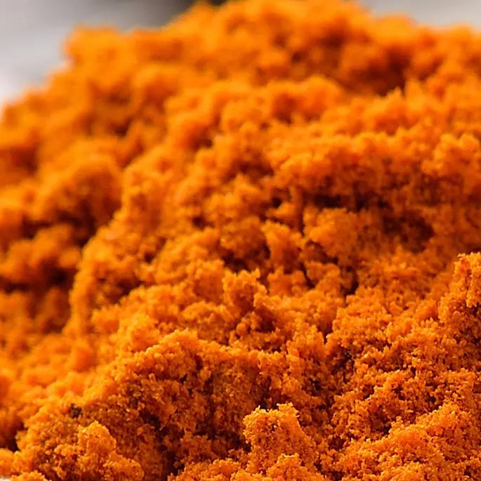 An orange powder on a spoon representing annatto