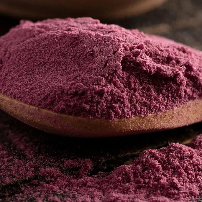 A purple-brownish powder on a spoon representing black carrot