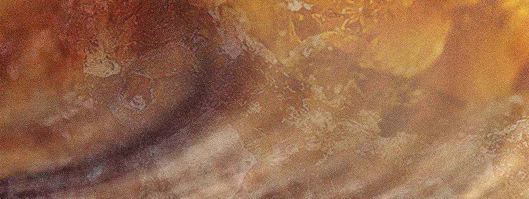 An abstract close-up of textured, swirling patterns in warm shades of amber and gold, creating a soft, ethereal appearance with subtle variations in light and shadow.
