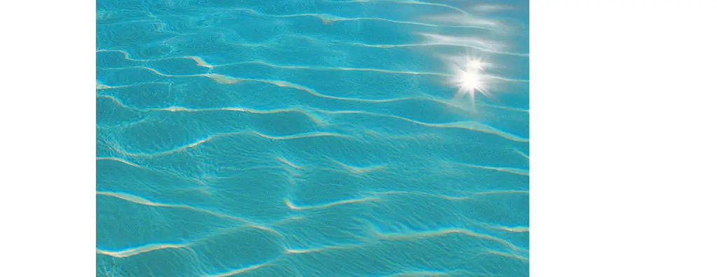 Clear turquoise water ripples gently under the sunlight, creating a serene and inviting atmosphere. 