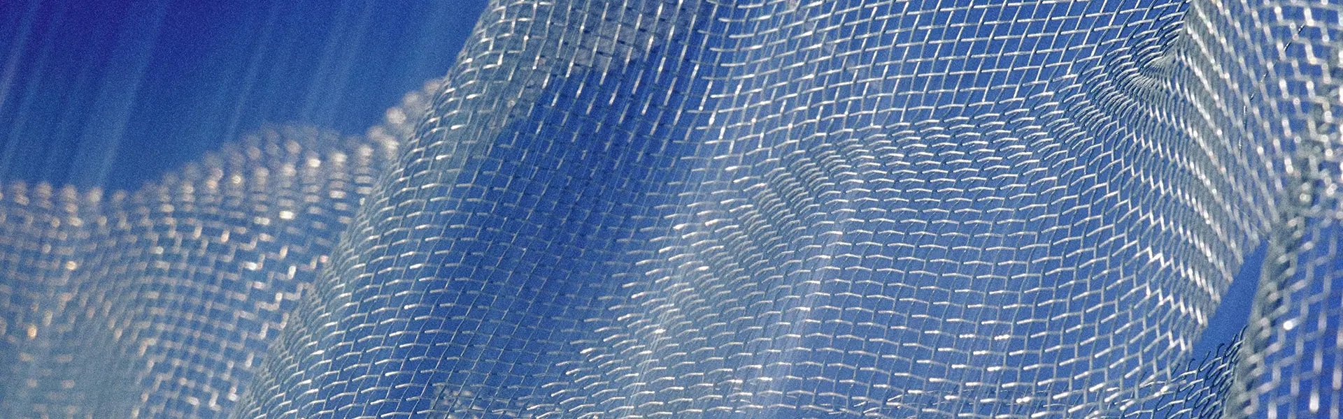 Translucent mesh fabric drapes softly, revealing a textured, grid-like pattern. The background features a calming blue hue, creating a serene atmosphere.