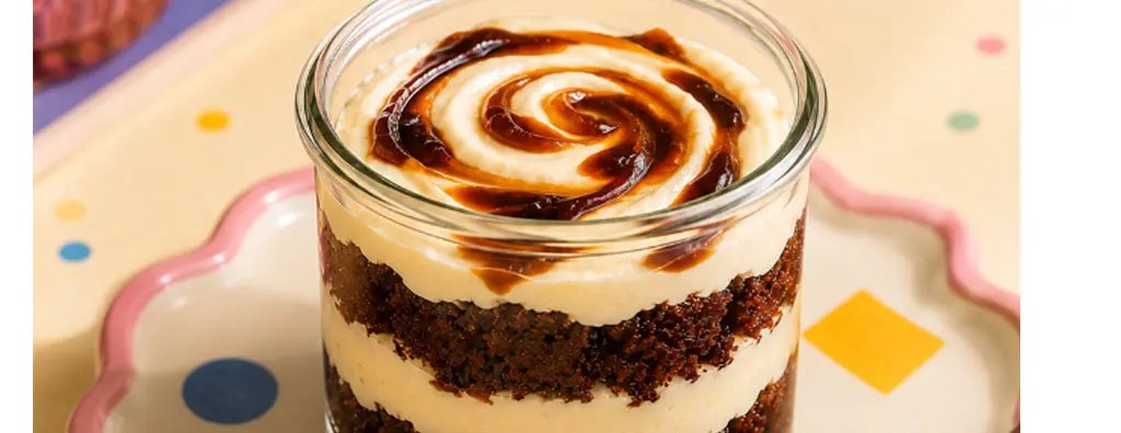 A glass jar contains layers of chocolate cake and creamy vanilla mousse, topped with a caramel swirl.