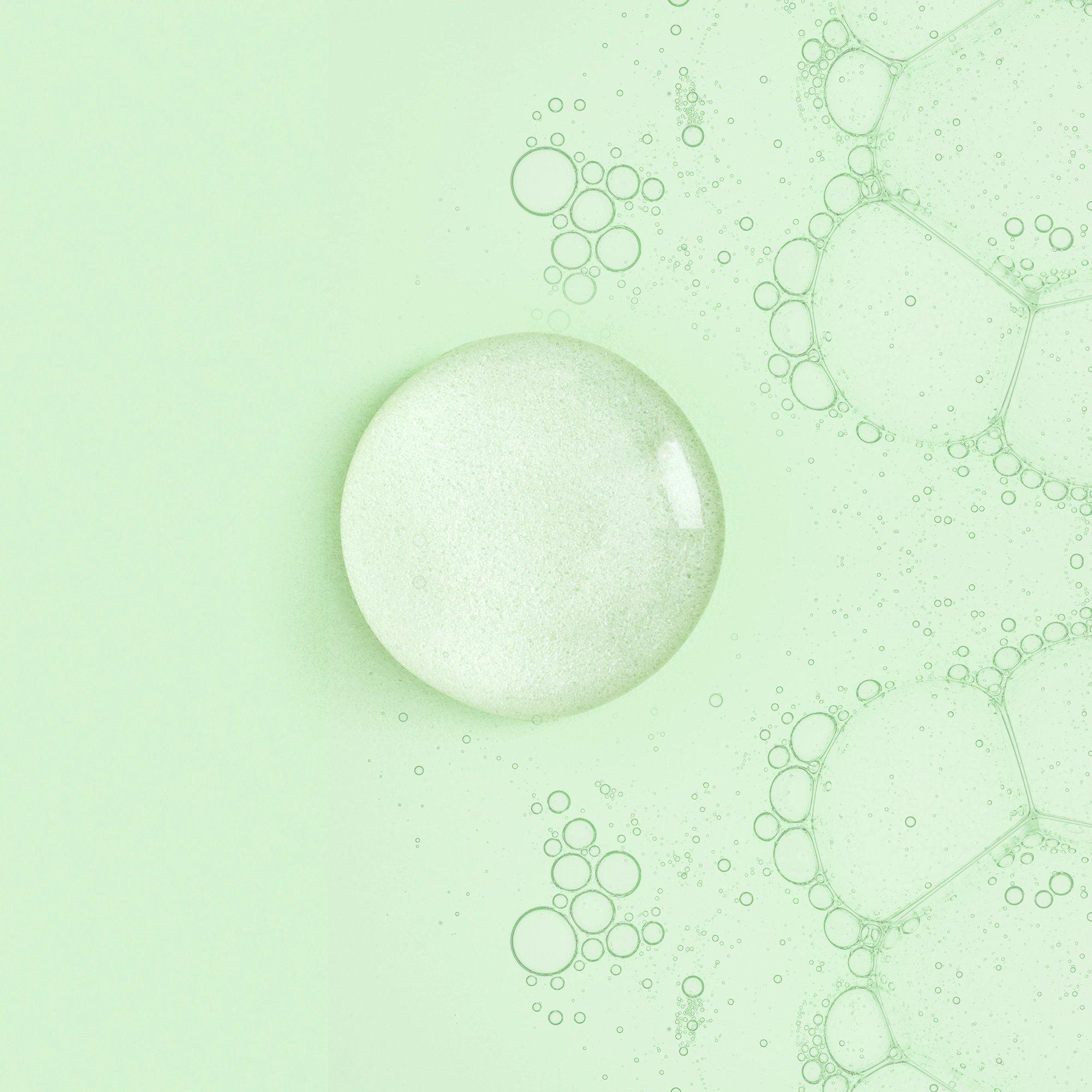 A pale green macro image of a large translucent bubble among clusters of smaller bubbles, evoking a fresh, calm, soap-like atmosphere.